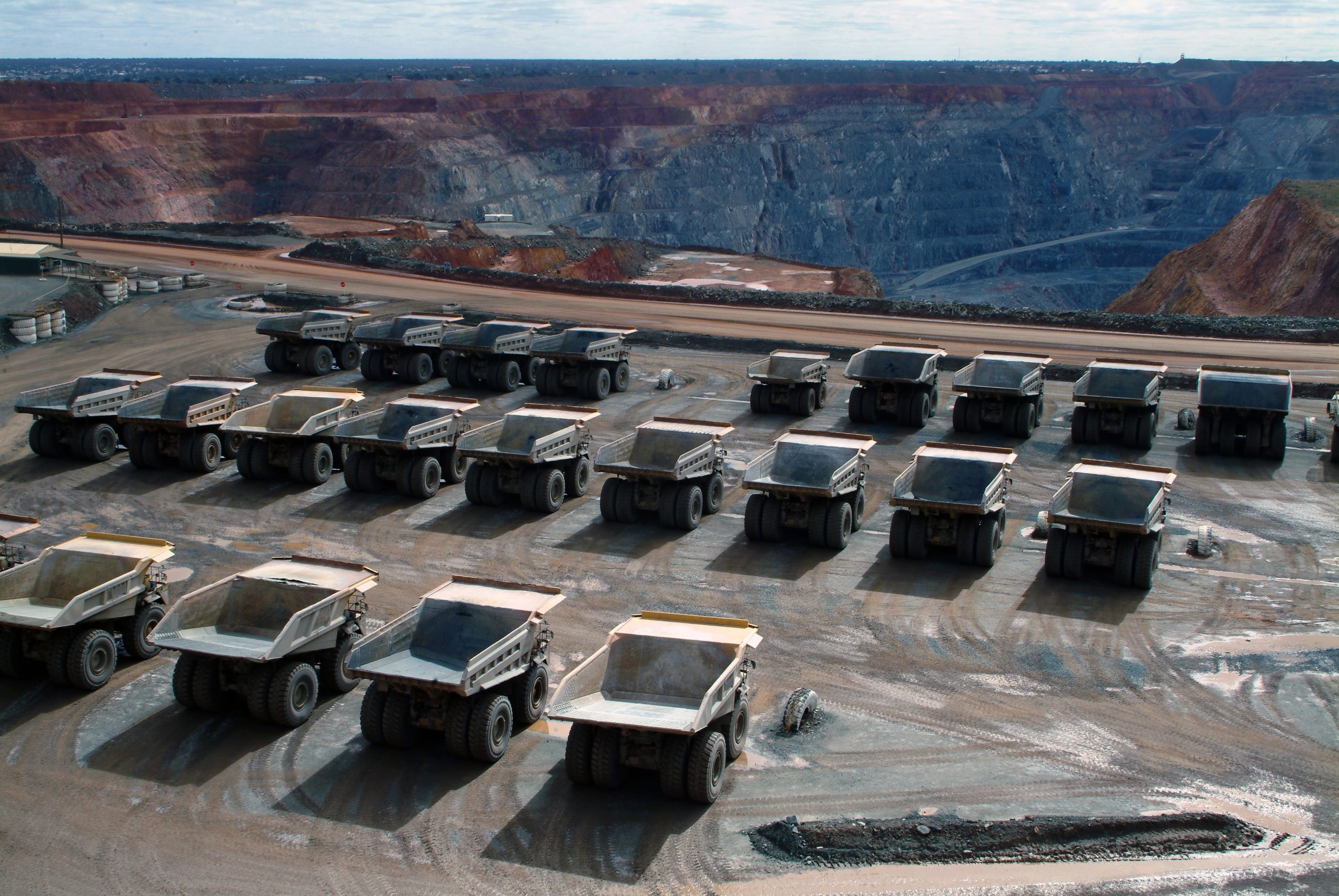 Many haul trucks parked in rows at a minesite.